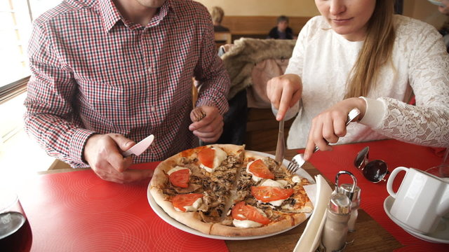 Couple eating pizza in restaurant