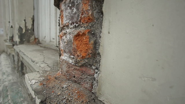Panning shot of weathered and deteriorating brickwork on an older colonial design building that needs construction repair.