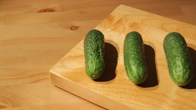 A set of fresh cucumbers on a cutting board dolly shot