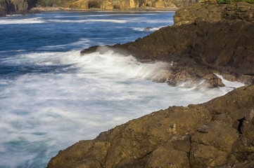 Waves breaking over dark rocks