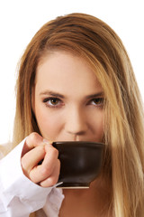 Woman in long sleeve shirt drinking coffee.