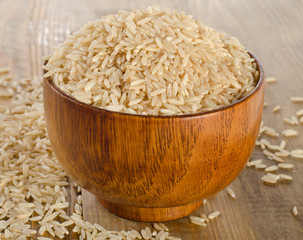 Raw uncooked brown rice in wooden bowl.