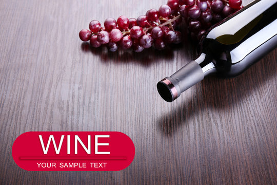 Bottle of wine with grape on wooden table