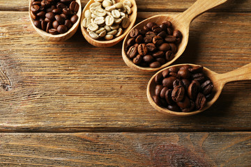 Coffee beans in spoons on wooden background