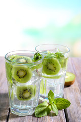 Glasses of cocktails on wooden table on bright blurred background