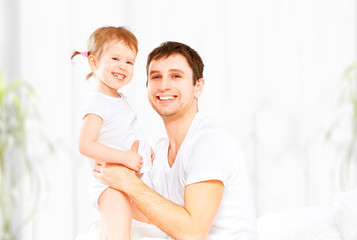 Happy family father and baby  daughter playing in bed