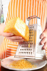 Closeup of female hands grating cheese