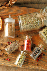 Assortment of spices in glass bottles on cutting board, on wooden background