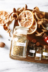 Assortment of spices in glass bottles on cutting board, on wooden background