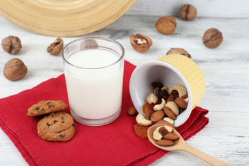 Milk in glassware with walnuts and cookies on wooden table, closeup