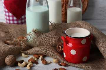 Milk in glassware and walnuts on wooden table with sackcloth, closeup