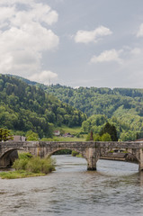 Fototapeta na wymiar Saint-Ursanne, St-Ursanne, Stadt, historische Steinbrücke, Brücke, Nepomuk, Doubs, Fluss, Schweiz