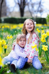 Cute happy little sisters hugging  in spring meadow