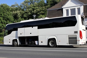 Reisebus mit geöffneten Gepäckfächern an Bushaltestelle