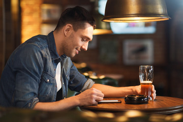 man with smartphone and beer texting at bar