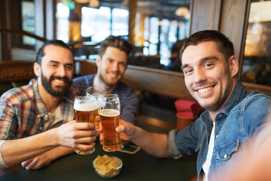 friends taking selfie and drinking beer at bar