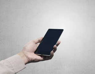 Hand holding cellphone with blank screen on grunge background