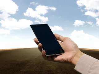 Hand holding cellphone with blank screen on empty road backgroun