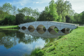 Fototapeta na wymiar White bridge in a lake in a Surrey park.