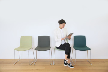 Woman in waiting room using digital tablet, concept