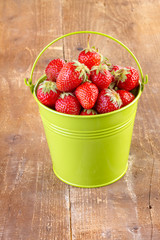 strawberry in a green metal bucket on wooden