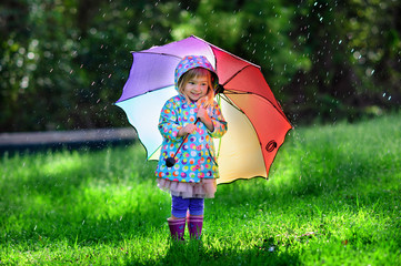 Funny cute toddler girl wearing waterproof coat with colorful um