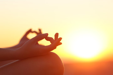 Woman hands exercising yoga at sunset