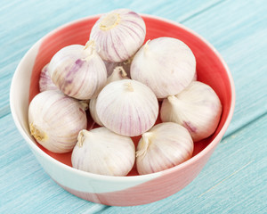 Garlic - A bunch of garlic bulbs in bowl a blue background.
