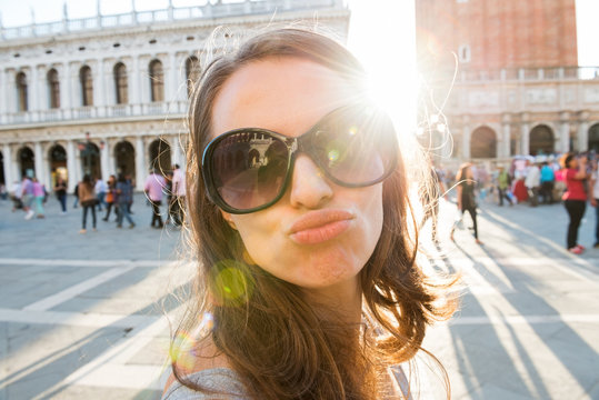 Woman tourist on St. Mark's Square taking selfie blowing a kiss