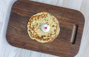 Fried round pancake with cream and berry on dark wood background.
Traditional home made or fast food dish stylish rough wooden desk