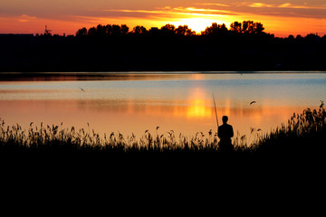 Fototapeta na wymiar Fisherman with a rod fishing at sunset