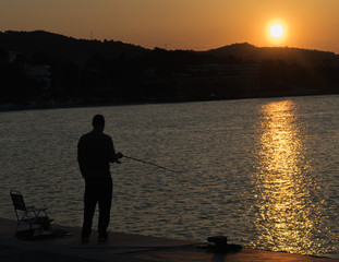 Fisherman chilling out against the beautiful sunset in Greece.