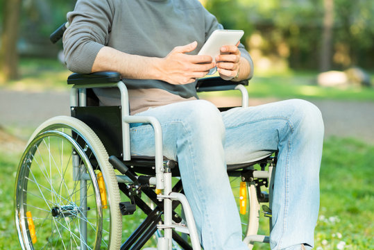 Detail of a man using a tablet on a wheelchair