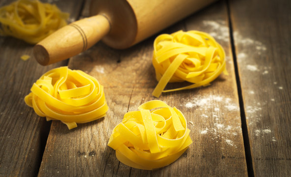  Italian pasta with fresh basil on the wooden surface. Selective focus