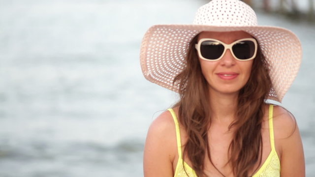 beautiful woman in sunglasses and big hat enjoying on sea
