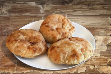 Plate with Pita Bread loafs and Baguette slices, on old Wood.