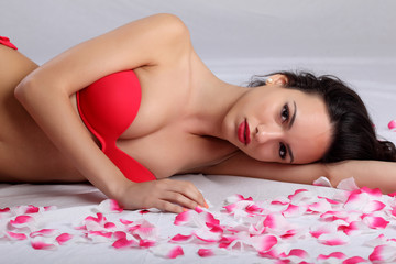 Obraz na płótnie Canvas Slim woman lying on roses petals 