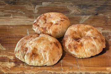 Three Pita Bread loafs and Baguette slices, on old Wood.