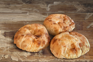 Three Pita Bread loafs, on old, weathered, cracked, peeled off, Wooden Table surface.