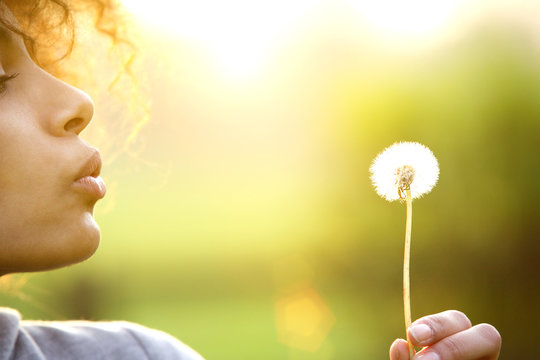 Young woman blowing dandelion flower outdoors