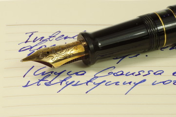 Fountain pen with gold, ornate nib on a notebook.