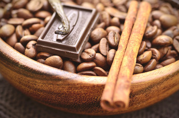Coffee beans with spices in a wooden bowl.