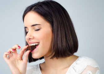 Portrait of the beautiful girl eating chocolate cookies isolated