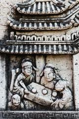 stone carving of family drinking tea