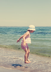 Little girl running and playing on the beach. The image is tinte