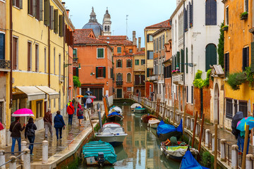 Fototapeta na wymiar Tourists under umbrellas on a rainy day in Venice