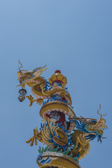 Colorful two dragons statue on pole with blue sky background.