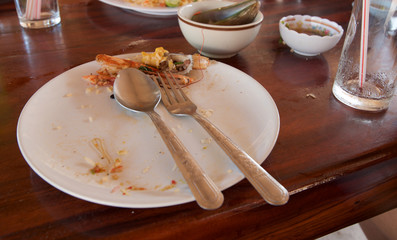 white dish with crumbs,used fork and used spoon
