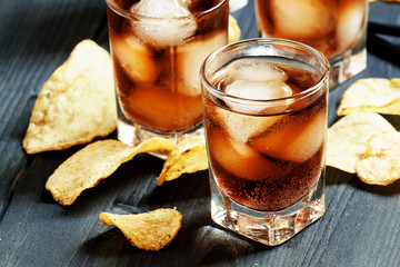 Cola with ice in glasses and chips, selective focus