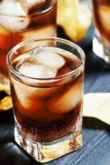 Cola with ice in glasses and chips, selective focus